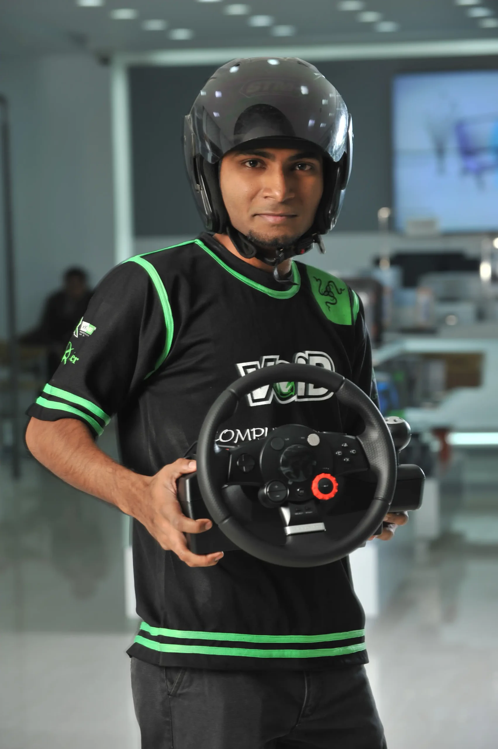 Customer posing with a racing wheel and helmet for Computer Source Ltd.